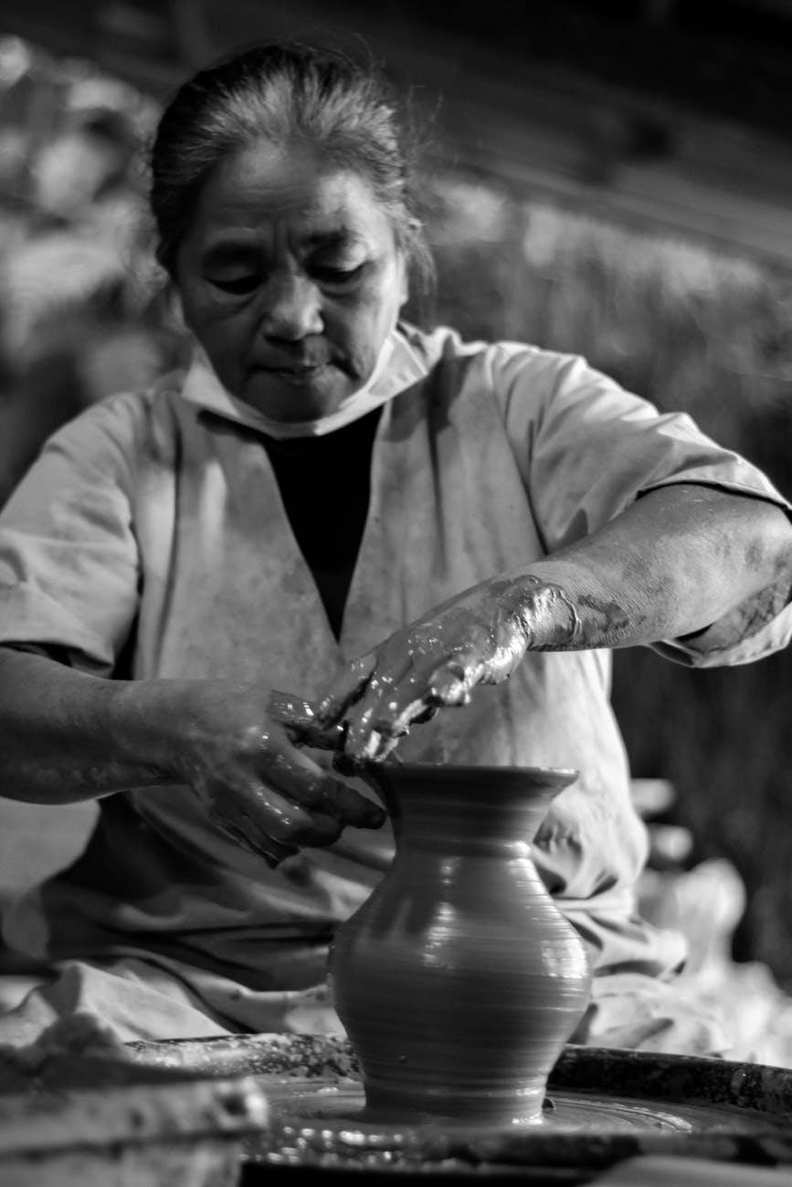 woman making clay pot grayscale photo